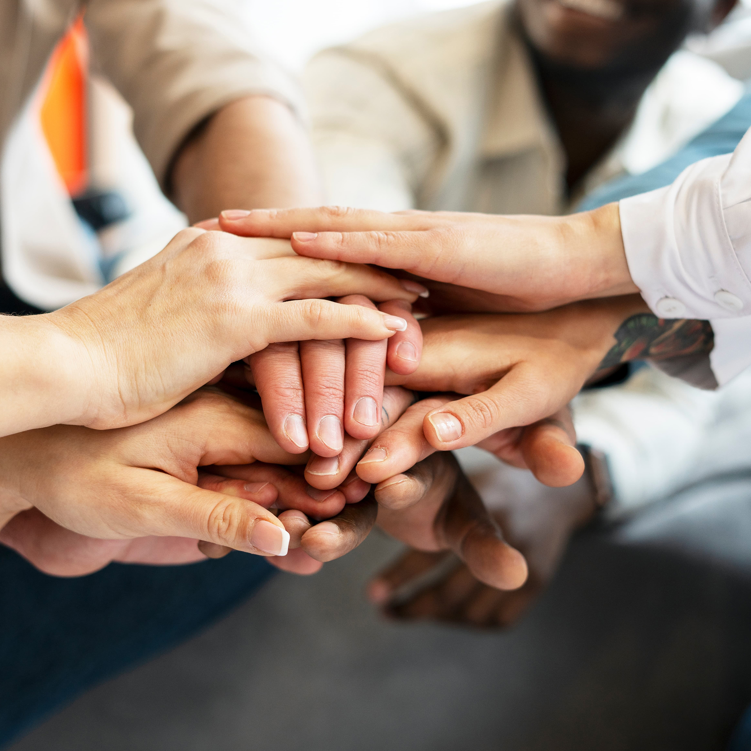 Mitarbeiter stapeln Hände aufeinander, als Zeichen der Gemeinschaftlichkeit und des Sozialen Engagements