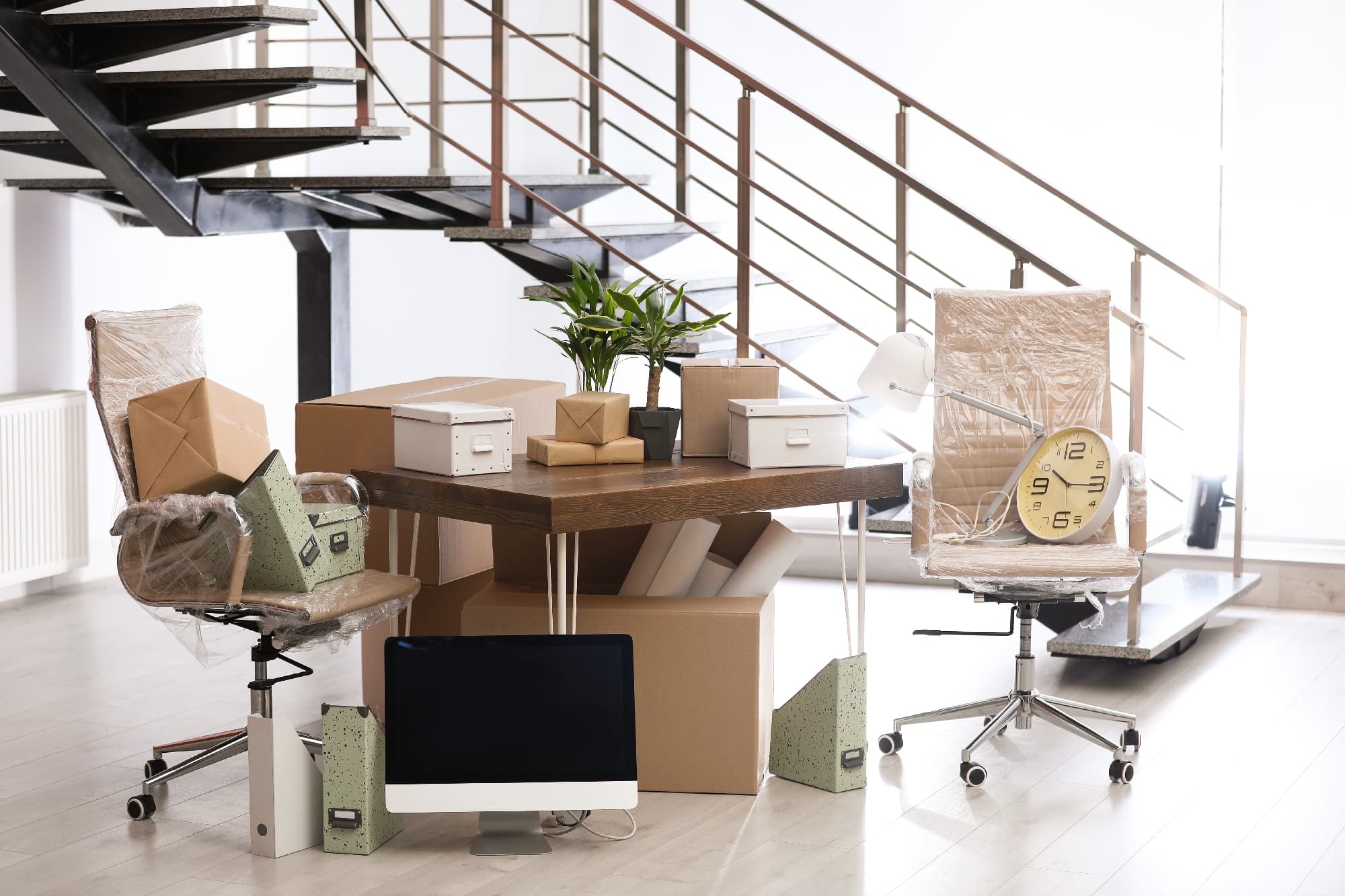 Büro mit Umzugskartons und gestapelten Möbeln und Utensilien